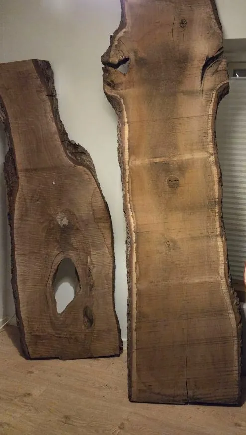 Two live-edge walnut slabs standing against a wall