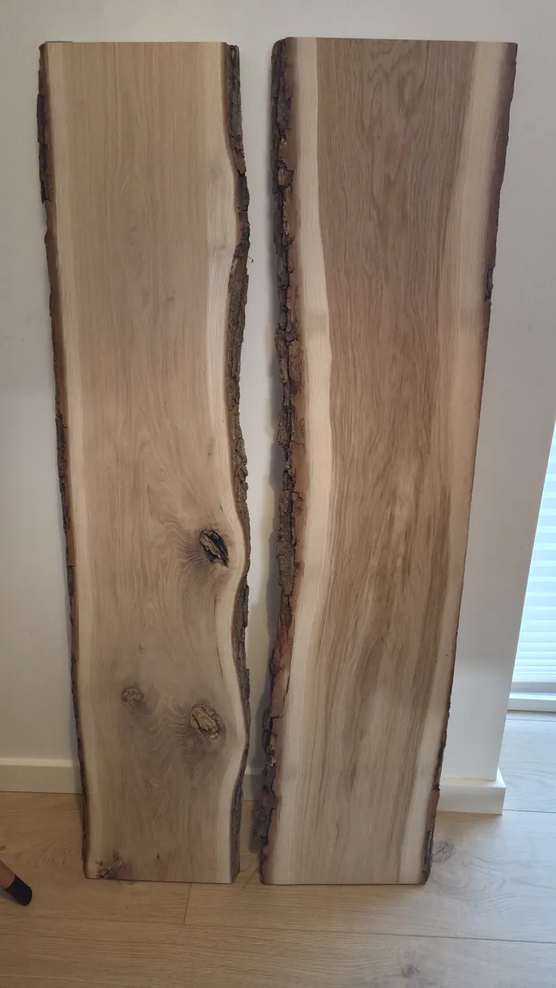 Two raw live-edge oak slabs standing against a wall